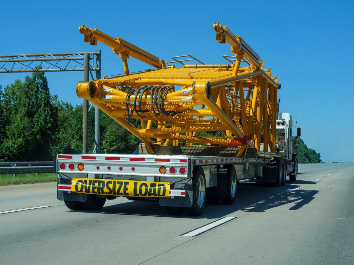 Semi truck with oversize load sign transporting industrial equipment on the highway